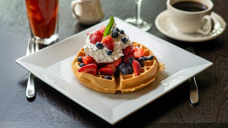 Waffle dessert topped with whipped cream and berries